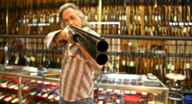 Jim Lauderdale takes aim in a Franklin gun shop.