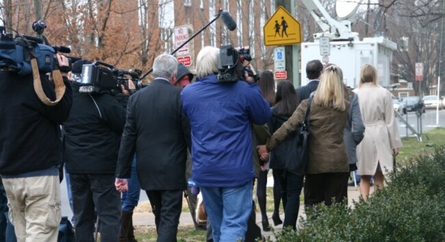Members of the media swarm outside the courthouse.