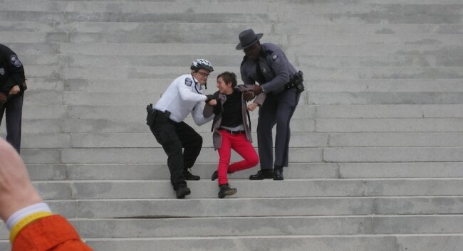 Police remove a person who refused to leave the steps of the state Capitol.