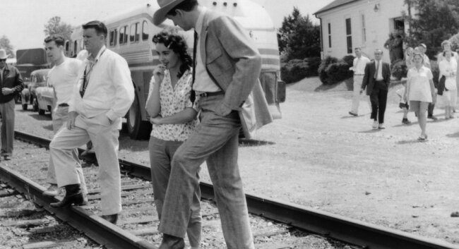 Rock Hudson, then 30, takes a break from filming at the Keswick railroad depot. Taylor, age 23, wasn%2526#039;t in the scene, as she is captured out of costume with her hair in curlers.