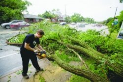 A samaritan in a C%2526amp;O shirt clears a tree from Ridge Street after a two years ago microburst