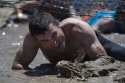 Petty Officer 3rd Class Sebastian McCormack, assigned to Fleet Combat Camera Group, Pacific, crawls through mud and under barbed wire-- the third obstacle of the May 2011 Tough Mudder event in Snow Valley, California. 
