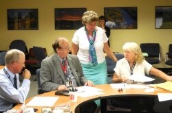 Charlottesville Electoral Board members Bob Hodous, Rick Sincere, and Joan Schatzman scrutinize ballots post-election with Registrar Sheri Iachetta (standing).