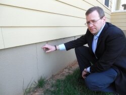 Rit Venerus points out a crack in the foundation of his Redwood Lane house that backs up to the airport.