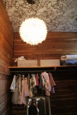 Never too young to dress well: A rustic closet off a nursery, created by Petit Bébé, added interest with wallpaper on the ceiling and an intricate hanging lamp.